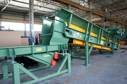 Apron conveyor industriale Ghirarduzzi con struttura inclinata e piastre metalliche, progettato per il trasporto continuo di materiali pesanti in fonderia o impianti di riciclo. Ideale per il carico dei forni o l’alimentazione di mulini.