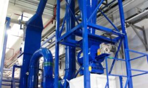 Blue zig zag industrial air separator by Ghirarduzzi SRL, designed for efficient separation of materials by density, used in recycling plants for metal recovery and plastic separation, shown in an indoor facility