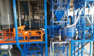 Angular view of a rubber granule separation plant with blue machinery and orange safety railings produced by Ghirarduzzi srl.